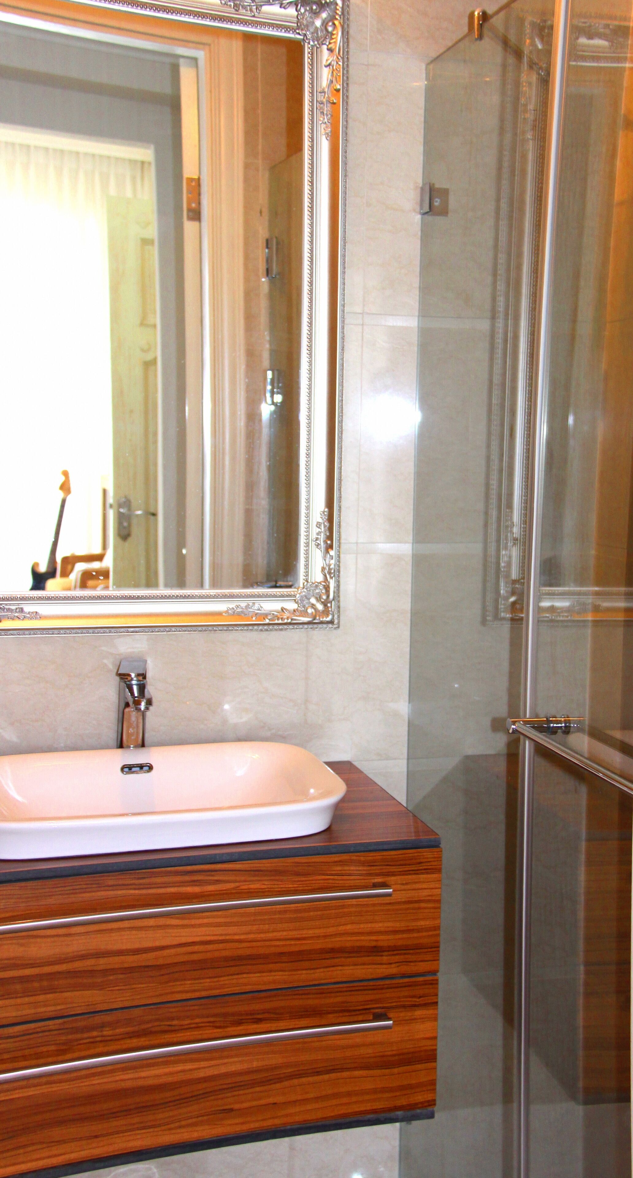Un baño con tocador de madera, un espejo grande y cabina de ducha de vidrio.