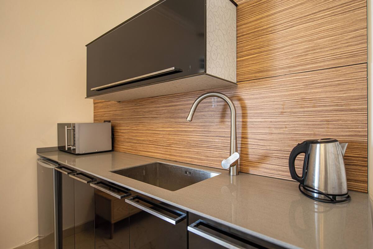 A modern kitchen with a stainless steel sink, a toaster, and a kettle.