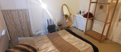 A bedroom with a bed, a dresser, a mirror, and a radiator.