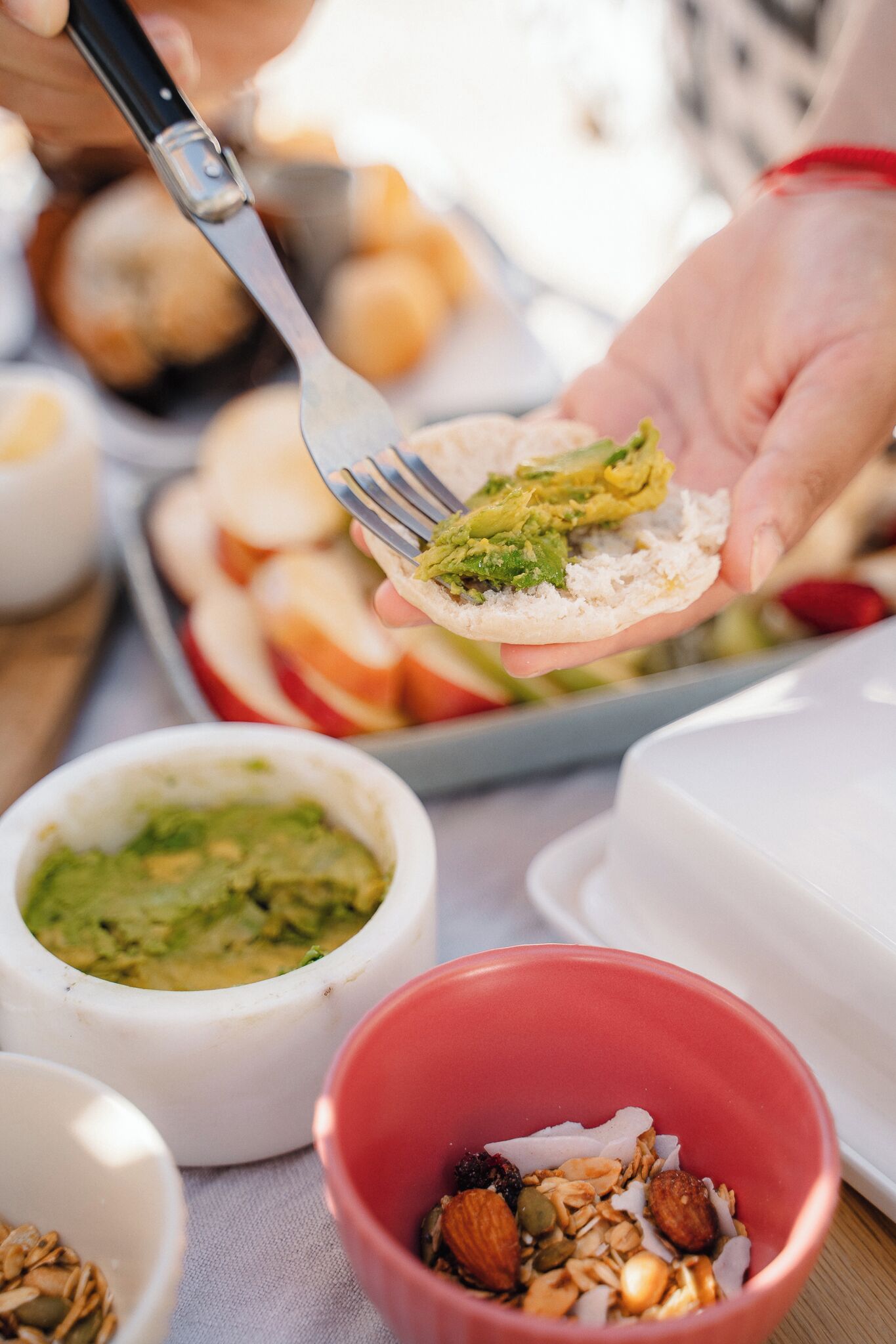 Una persona sosteniendo un tenedor con un sándwich, rodeada de tazones con comida.