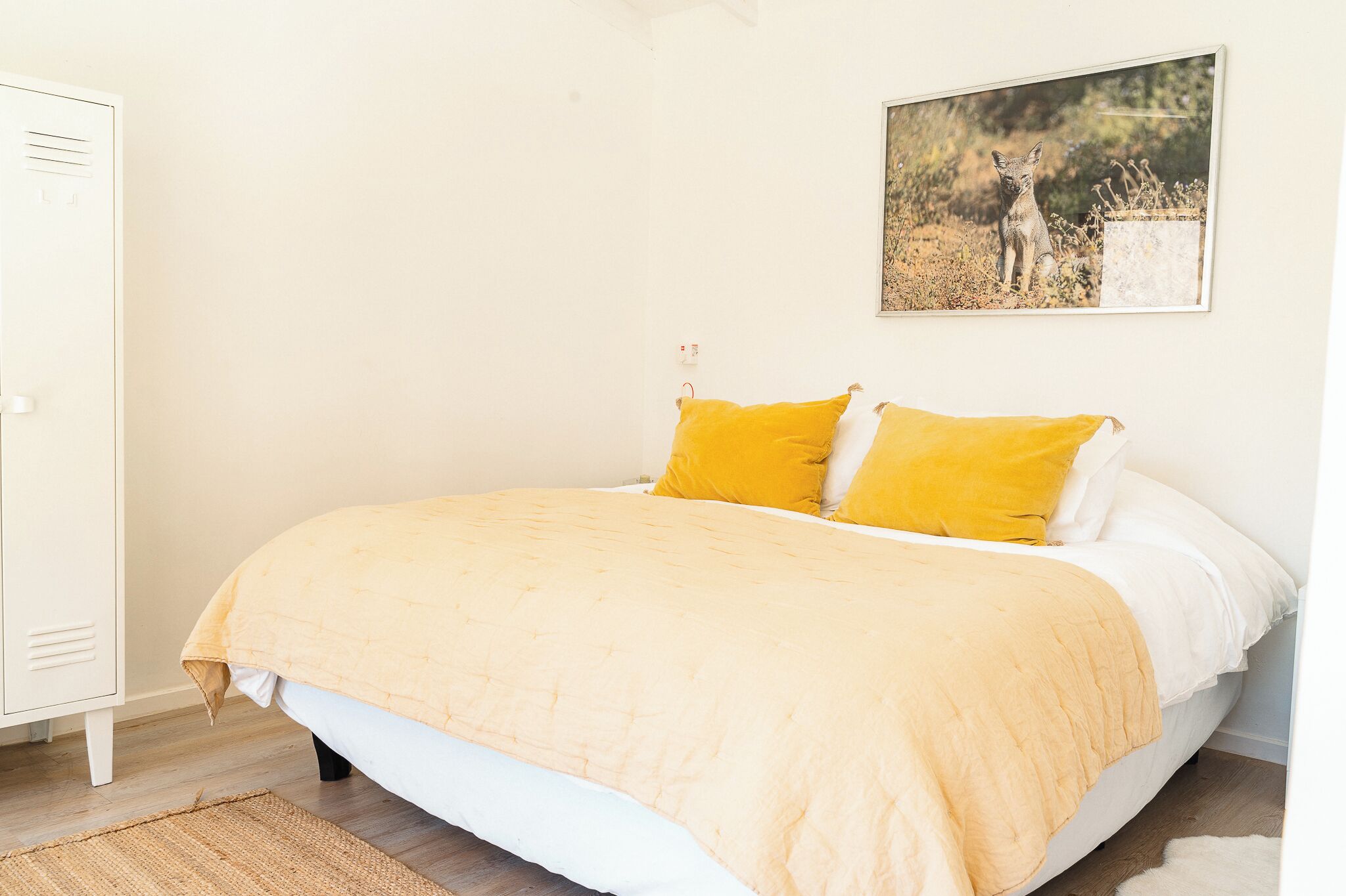A bedroom with a bed, a white wardrobe, and a framed picture on the wall.