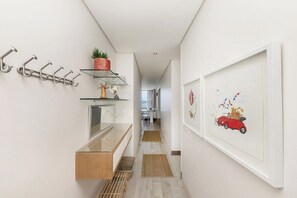 Ein Flur mit Kleiderständer, Regalen mit Dekoration, einem gerahmten Bild und einer hölzernen Bank.