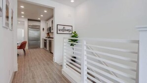 Una cocina moderna con un refrigerador de acero inoxidable, un cartel de bienvenida y una planta en maceta.