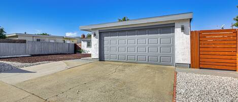 A residential garage with a concrete driveway and a gravel area.