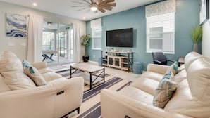 A modern living room with a sofa set, a coffee table, a TV, and a ceiling fan. - 14 Mi to Wdw: Family-friendly Home w/ Movie Room! (Kissimmee)