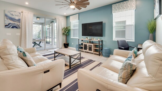 A modern living room with a sofa set, a coffee table, a TV, and a ceiling fan. - 14 Mi to Wdw: Family-friendly Home w/ Movie Room! (Kissimmee)