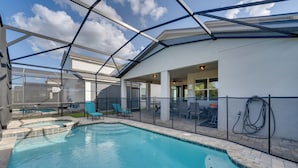 A swimming pool with a glass enclosure, lounge chairs, and a covered patio area. - 14 Mi to Wdw: Family-friendly Home w/ Movie Room! (Kissimmee)