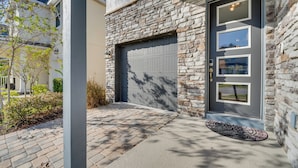 A modern house with a stone facade, a garage door, and a doormat. - 14 Mi to Wdw: Family-friendly Home w/ Movie Room! (Kissimmee)