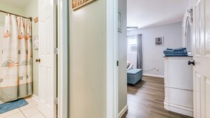 Un corridoio con una porta che dà su una camera da letto, una panca imbottita blu e un armadietto bianco.