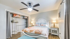 Una camera da letto con un letto, comodini, una ventola a soffitto e un armadio.