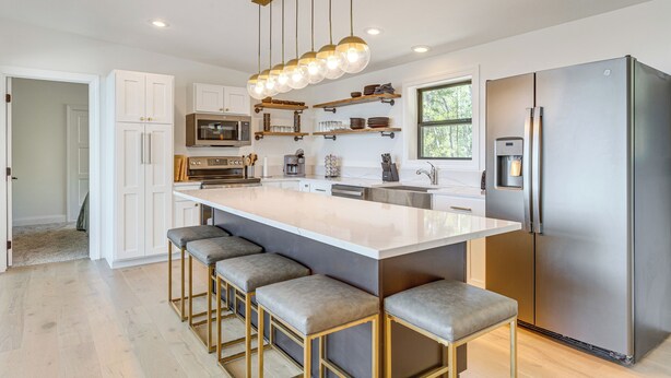 A modern kitchen with a large island, bar stools, stainless steel appliances, and pendant lighting. - 3 Mi to Fairplay Beach: Mountain Getaway (Fairplay)
