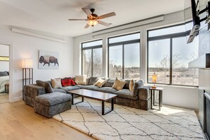Una sala de estar moderna con un sofá modular, una mesa de centro y un amplio ventanal con vistas al exterior.