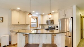 A kitchen with a central island, stainless steel appliances, wooden cabinets, and pendant lighting. - 5 Mi to Whitefish Resort: Getaway w/ Shared Patio (Whitefish)