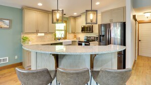 A modern kitchen with a central island, stainless steel appliances, and pendant lighting.
