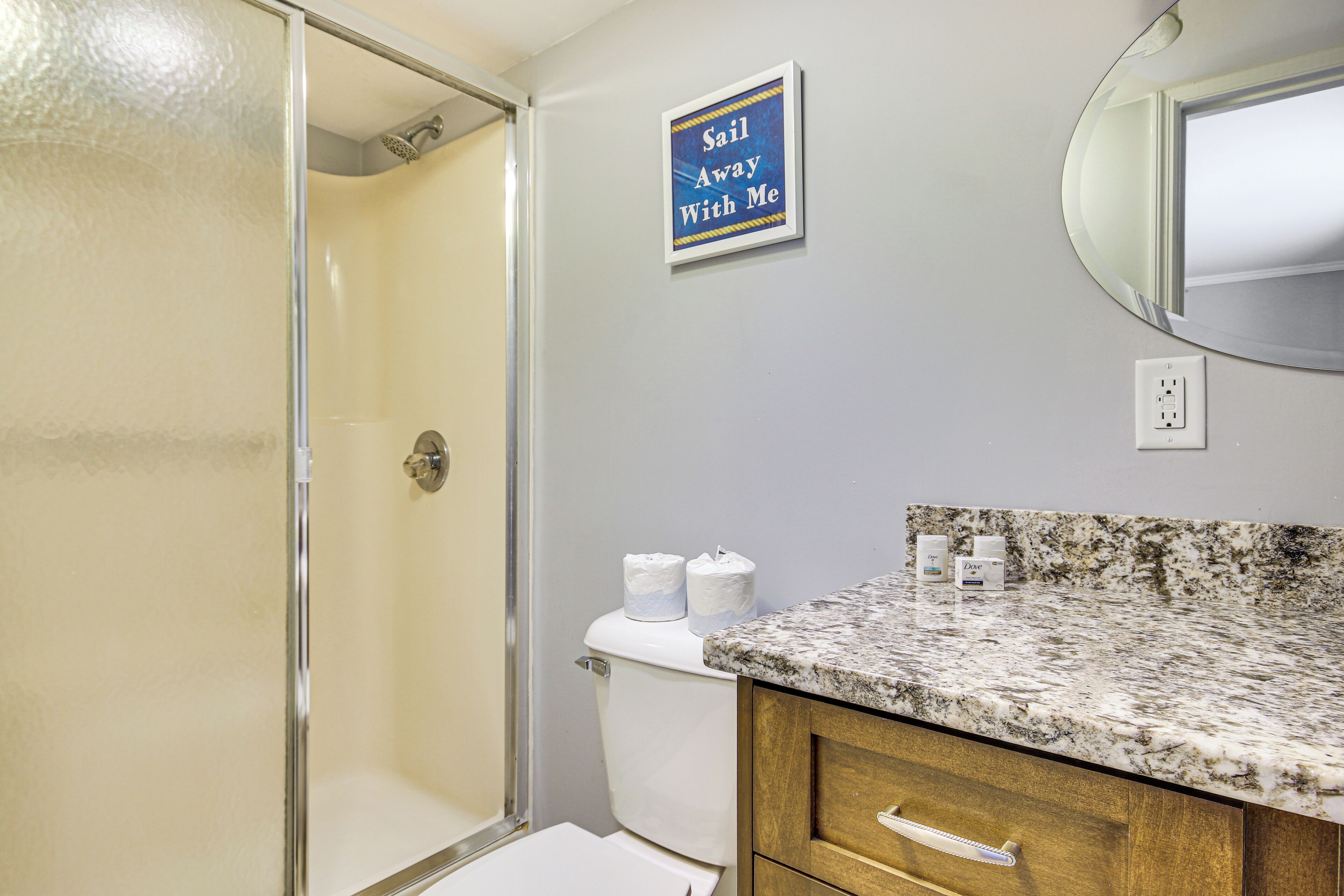 A bathroom with a shower, toilet, and a vanity with a mirror.