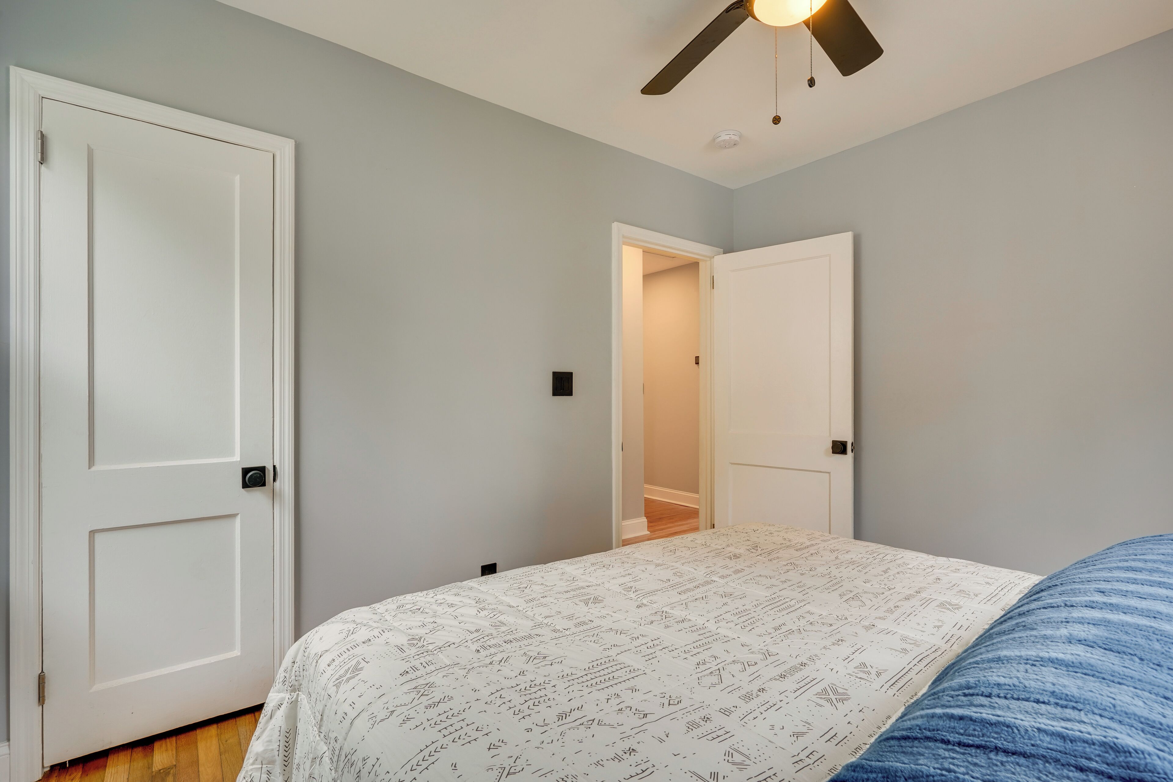 A bedroom with a bed, a ceiling fan, and two doors.