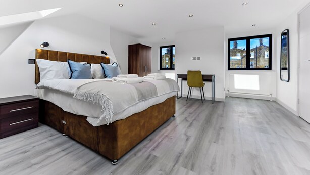 Une chambre à coucher moderne avec un grand lit, un bureau et une chaise.