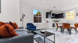 Un salon moderne avec un canapé gris, un fauteuil bleu et une table basse.