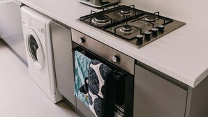 Une cuisine moderne équipée d’une cuisinière en acier inoxydable, d’un lave-linge et d’un évier.