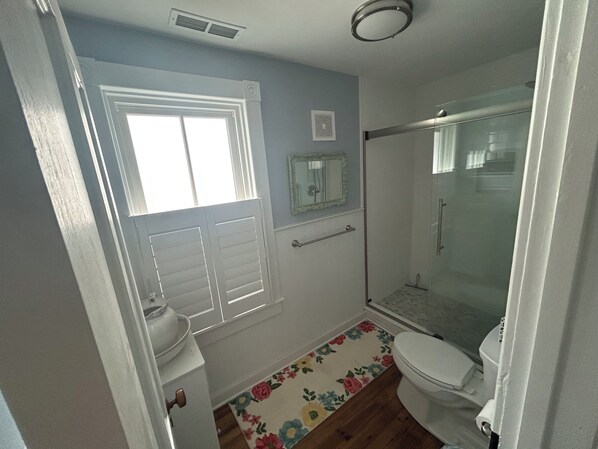 A bathroom with a shower, toilet, and sink.