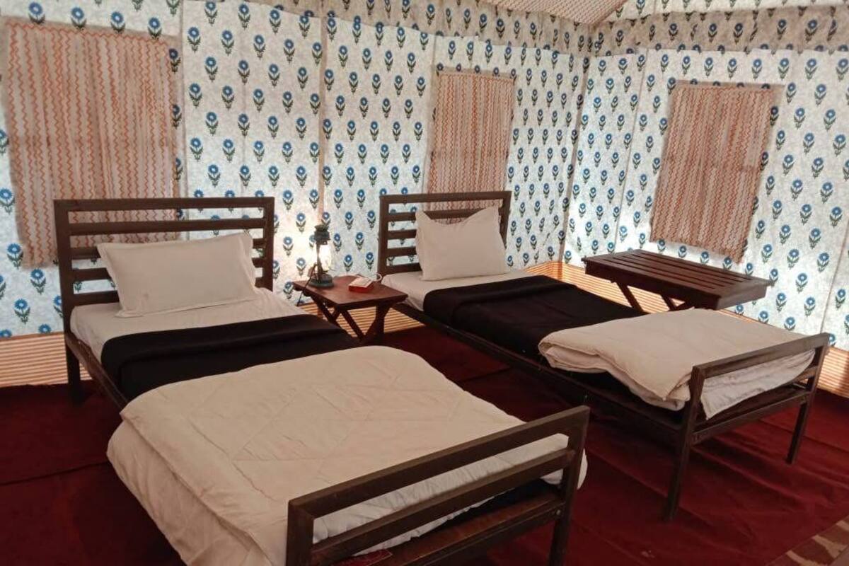 A room with two beds, a small table, and curtains.