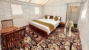 Una camera tenda con un letto, mobili in legno, una ventola e tappeti decorati.
