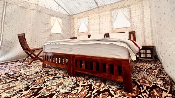 Una stanza con un letto, una sedia e un tavolino.