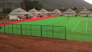 Un campo sportivo con tende e bandiere, circondato da una recinzione.