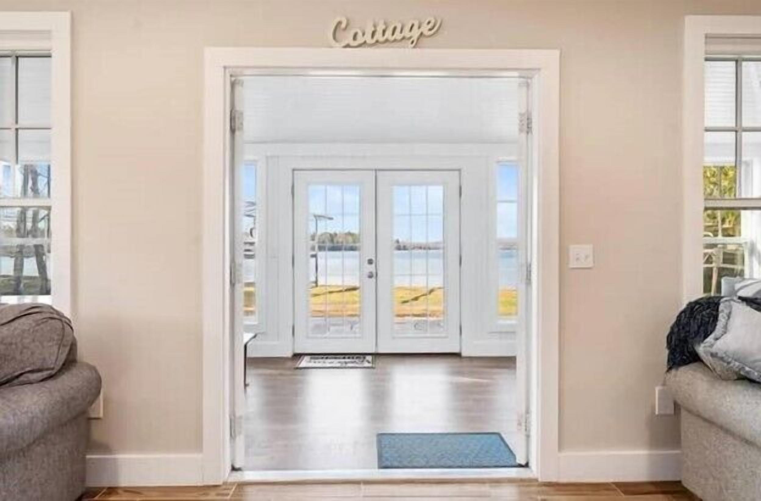 A door labeled "Cottage" leading to a room with a view of a beach.