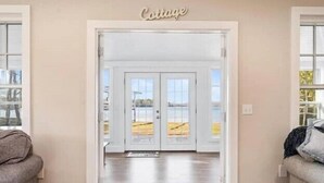 Une porte portant l’inscription « Cottage » qui donne sur une pièce offrant une vue sur la plage.
