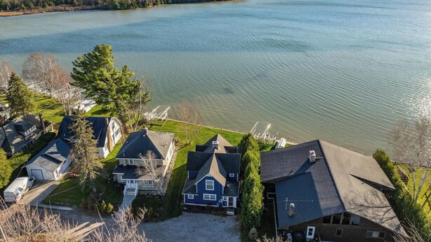 Un quartier résidentiel avec des maisons situées près d’une étendue d’eau importante, entouré d’arbres et de collines.