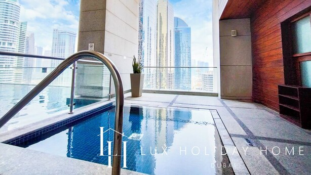 A luxurious indoor swimming pool with a city view, modern architecture, and a clear sky. - LUX  The Bonnington JLT Suite 2 (Dubai)