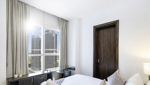 A hotel room with a bed, bedside table, lamp, and a large window with curtains. - LUX  The Bonnington JLT Suite 2 (Dubai)