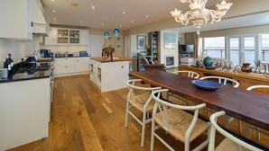 Une cuisine spacieuse avec un îlot central en bois, des meubles de cuisine blancs et un lustre.