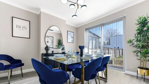 En matplats med ett glasbord, blå stolar och ett stort fönster med utsikt över omgivningen.