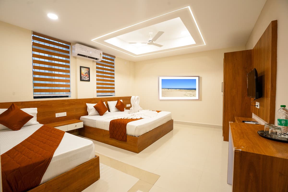 A hotel room with two beds, a ceiling fan, an air conditioning unit, a desk with a chair, and a window with a beach view.