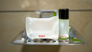 Een wastafel met een zeepstuk en een shampoo flacon.