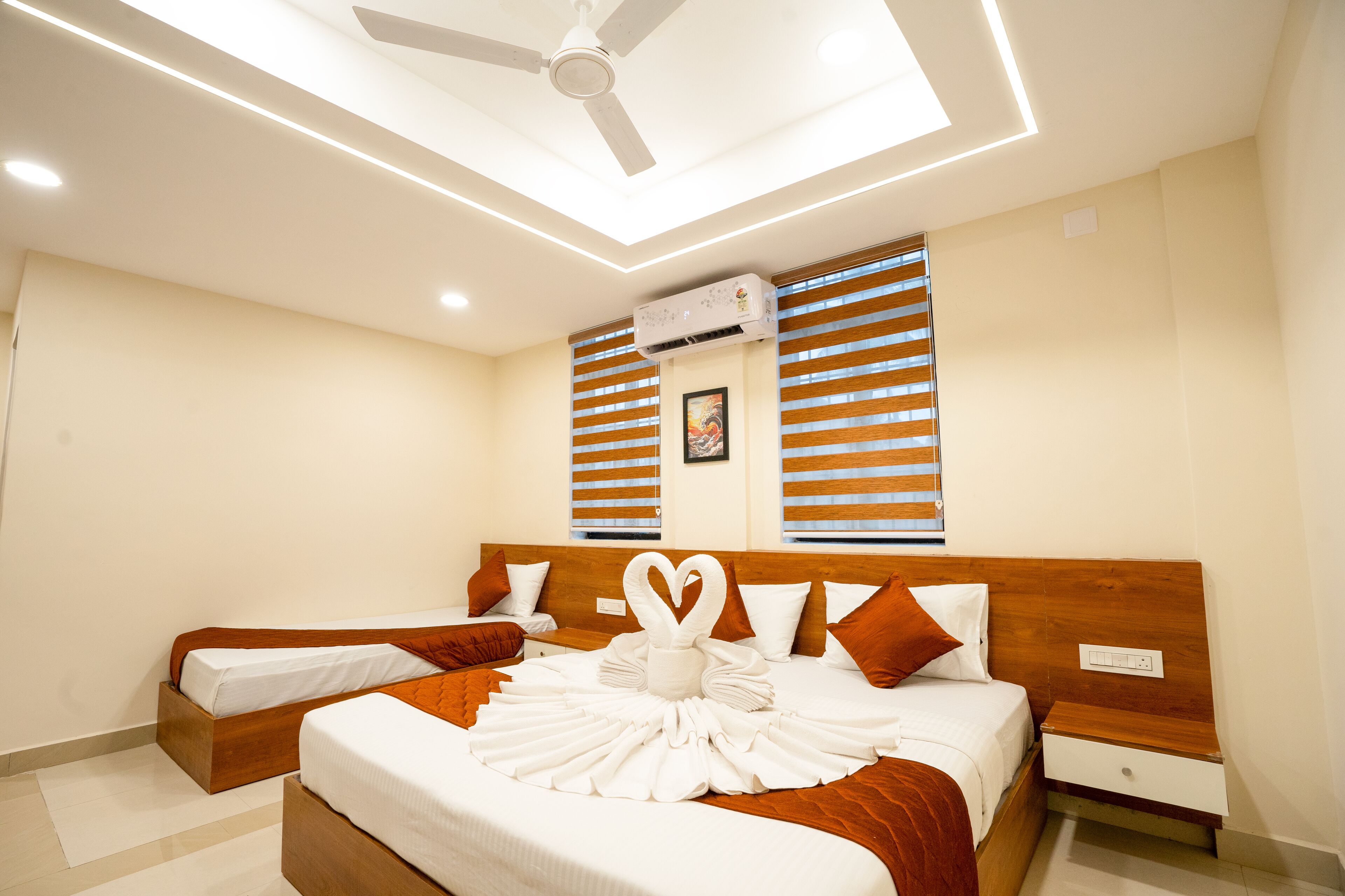 Ein Hotelzimmer mit Bett, Nachttisch, Deckenventilator und Klimaanlage.