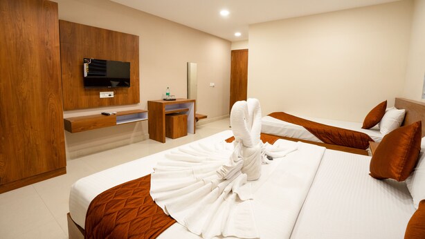 Een hotelkamer met twee bedden, een aan de muur bevestigde televisie, een houten bureau en een spiegel.