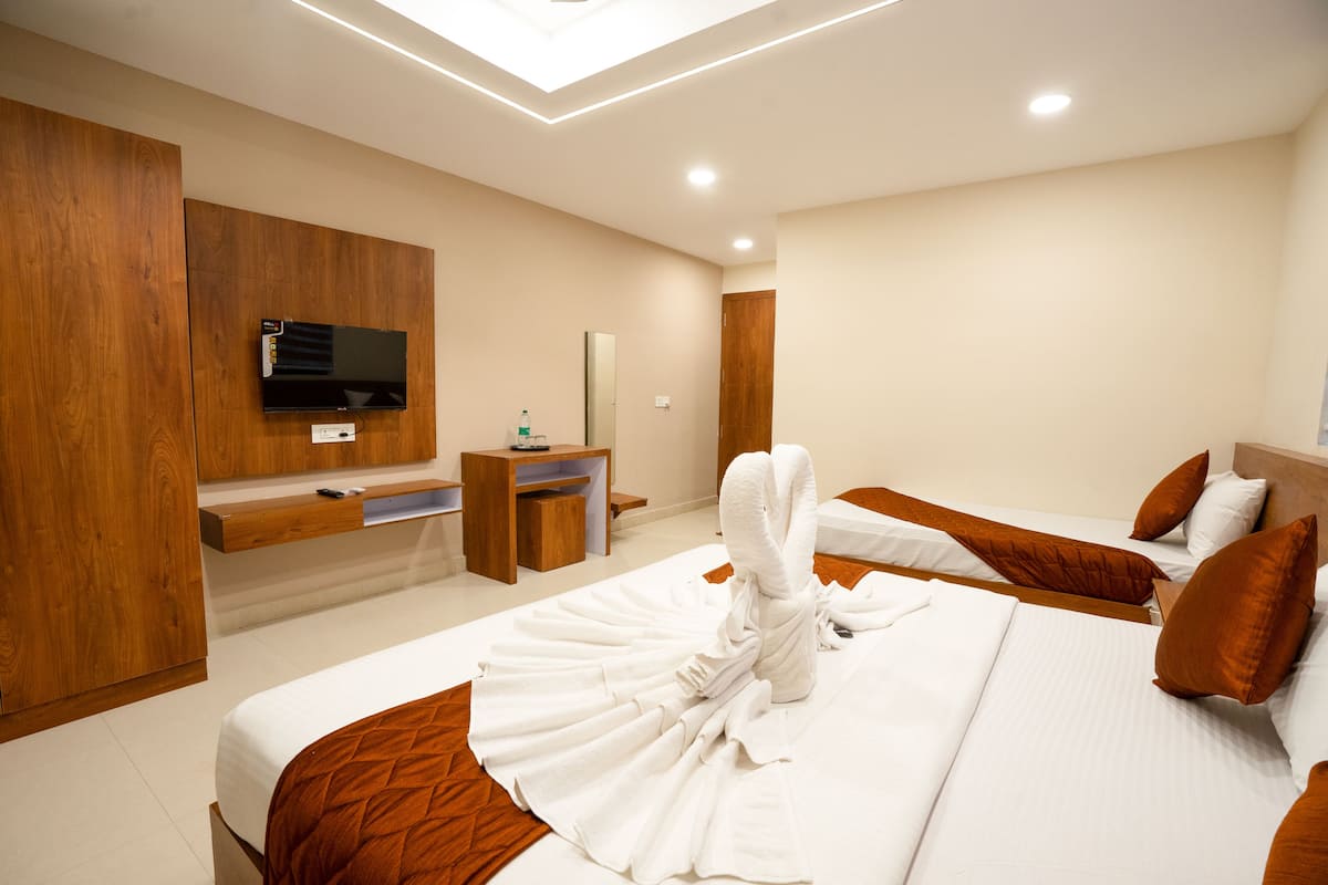 A hotel room with two beds, a TV mounted on the wall, a wooden desk, and a mirror.