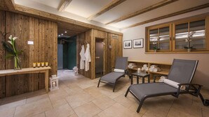 Une salle de spa aux murs en bois, avec deux fauteuils inclinables, une petite table avec des articles de toilette et une fenêtre ornée de cadres avec des photos.