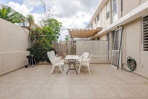 A patio with a table and chairs, a grill, and a hose. - Ginger House. Charming 3-bedroom townhome, fast WiFi, A/C in enchanting Rincón (Rincón)