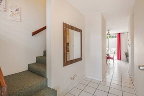 Una escalera conduce a un cuarto con un espejo grande y un comedor visible al fondo.