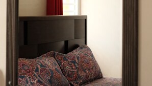 A bed with a headboard, a wall-mounted light fixture, and a window with red curtains. - Ginger House. Charming 3-bedroom townhome, fast WiFi, A/C in enchanting Rincón (Rincón)