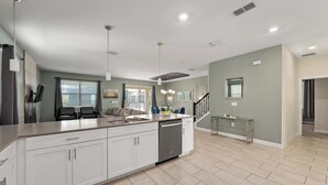 A modern kitchen with a large island, built-in appliances, and a dining area with a staircase.