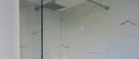 Une salle de bain moderne avec une douche à parois de verre, des toilettes et des murs en marbre.