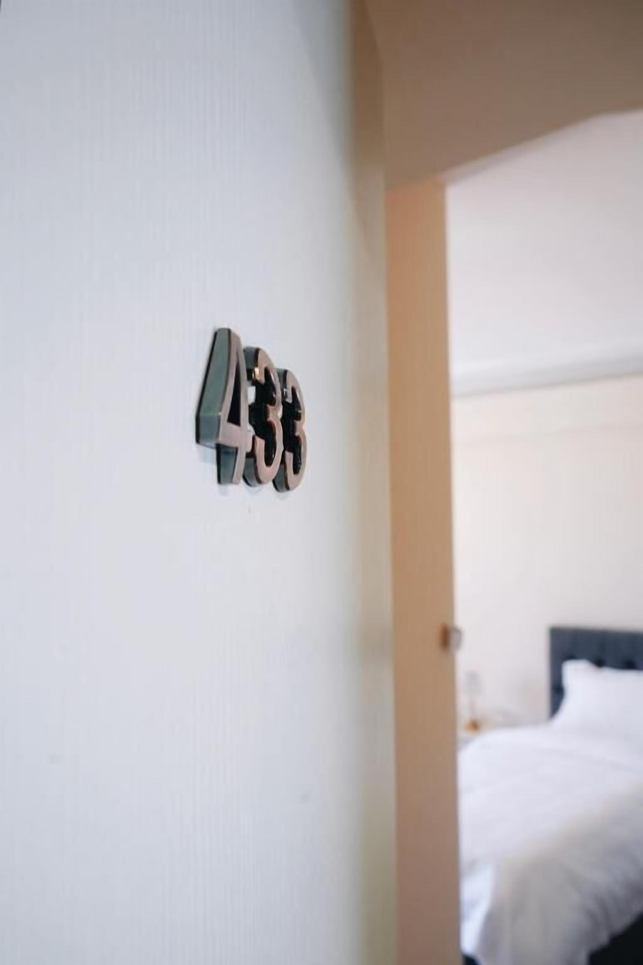 A hotel room with a bed and a wall-mounted number sign.
