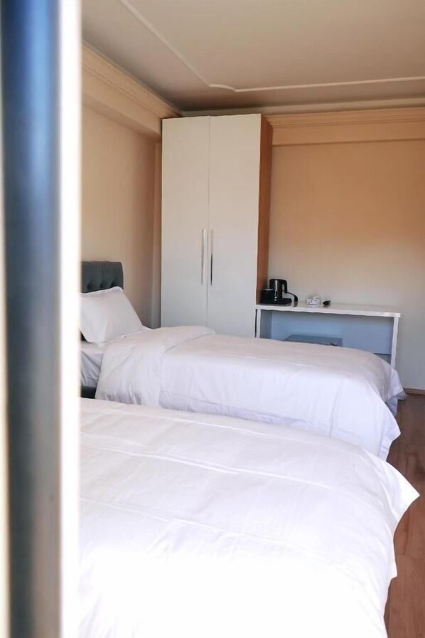 Una habitación de hotel con dos camas, un armario y un escritorio con cafetera.