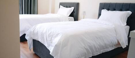 A hotel room with two beds, each with a dark headboard and white bedding.