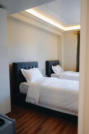 Een hotelkamer met twee bedden, houten vloeren en een modern design.